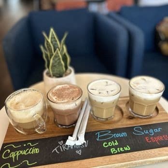 Koffee Paradise coffee flight with cappuccino, tiramisu, brown sugar cold brew and espresso drinks on a wooden board
