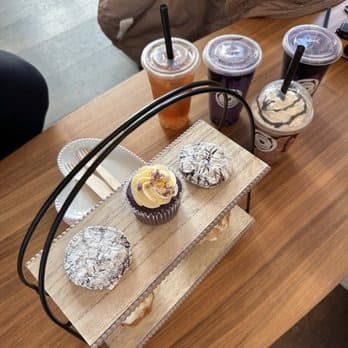 Ube cupcake and crinkle cookies on a wooden tray with iced drinks